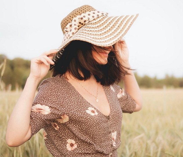 picture of a woman on a field wearing a dress and a hat 