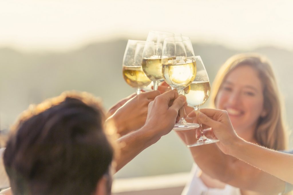 Group of friends drinking white wine and making a celebration toast outdoors