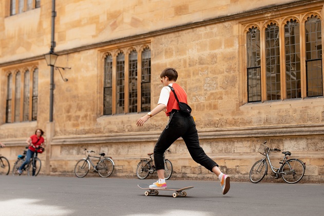 picture of woman on skateboard and another on a bicycle 