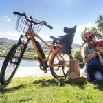 picture of woman with a baby boy beside a bicycle in a park beside water