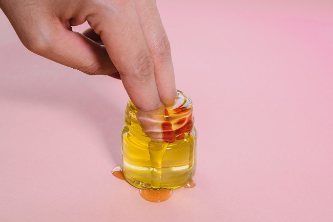 picture of persons fingers in an oil based lubricant on a purple background 