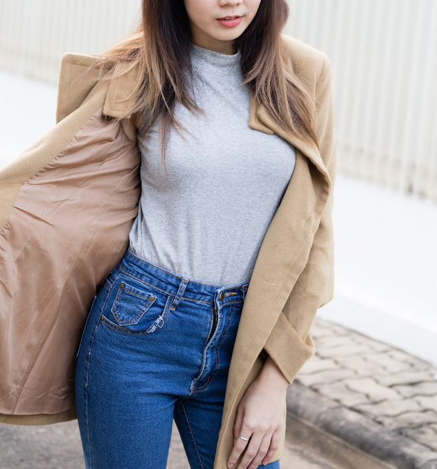 teen girl waering grey turtleneck, brown coat and denim jeans