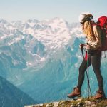 Woman wearing travel backpack while hiking on the top of the mountain