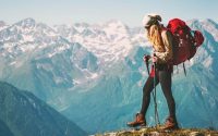 Woman wearing travel backpack while hiking on the top of the mountain