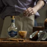 Bartender preparing a cocktail with Don Roberto 1924 tequila and fresh coconut.